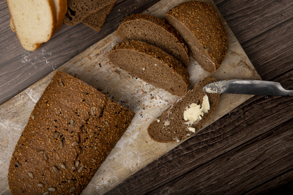 Birazı dilimlenmiş çavdar ekmeği, 1 dilimin üzerine tereyağı sürülmüş