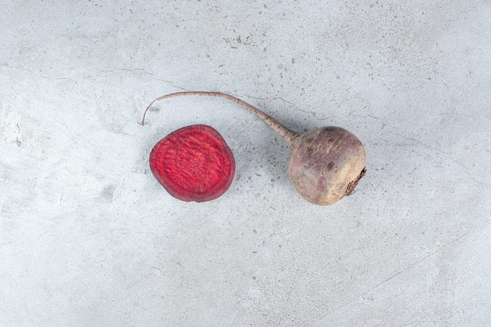 Masanın üzerinde duran bir tam bir de kesilmiş 2 adet pancar.