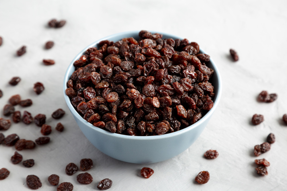 Bir kase kuru üzüm, birazı masada.