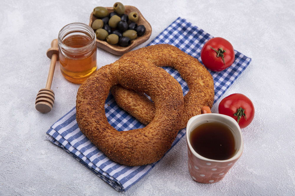 2 adet simit, yanında zeytin, domates, bal ve çay.