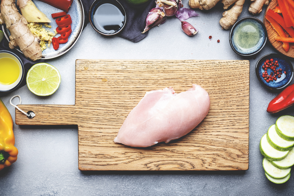 Kesme tahtasının üzerinde bir parça tavuk göğsü